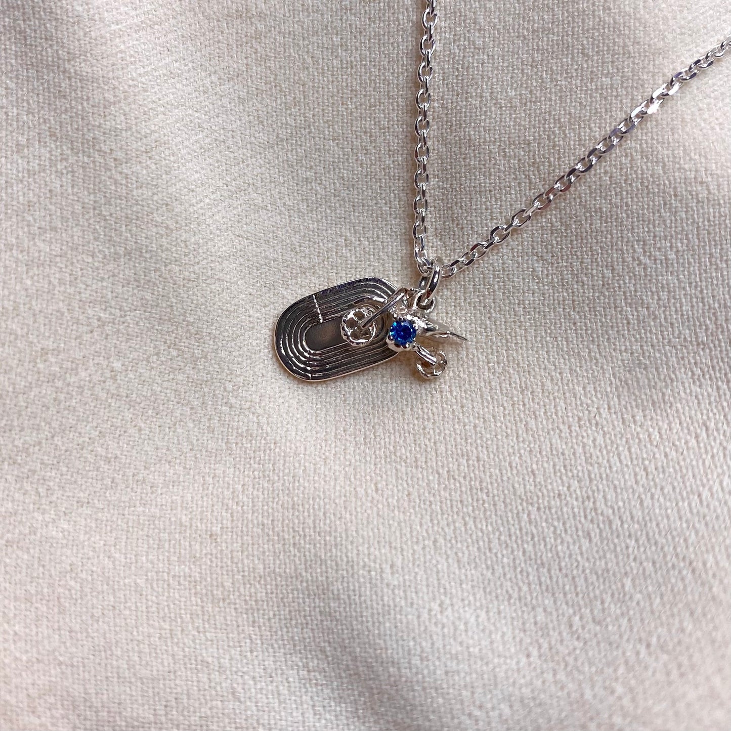 Ciondolo con moto da cross e pista di atletica