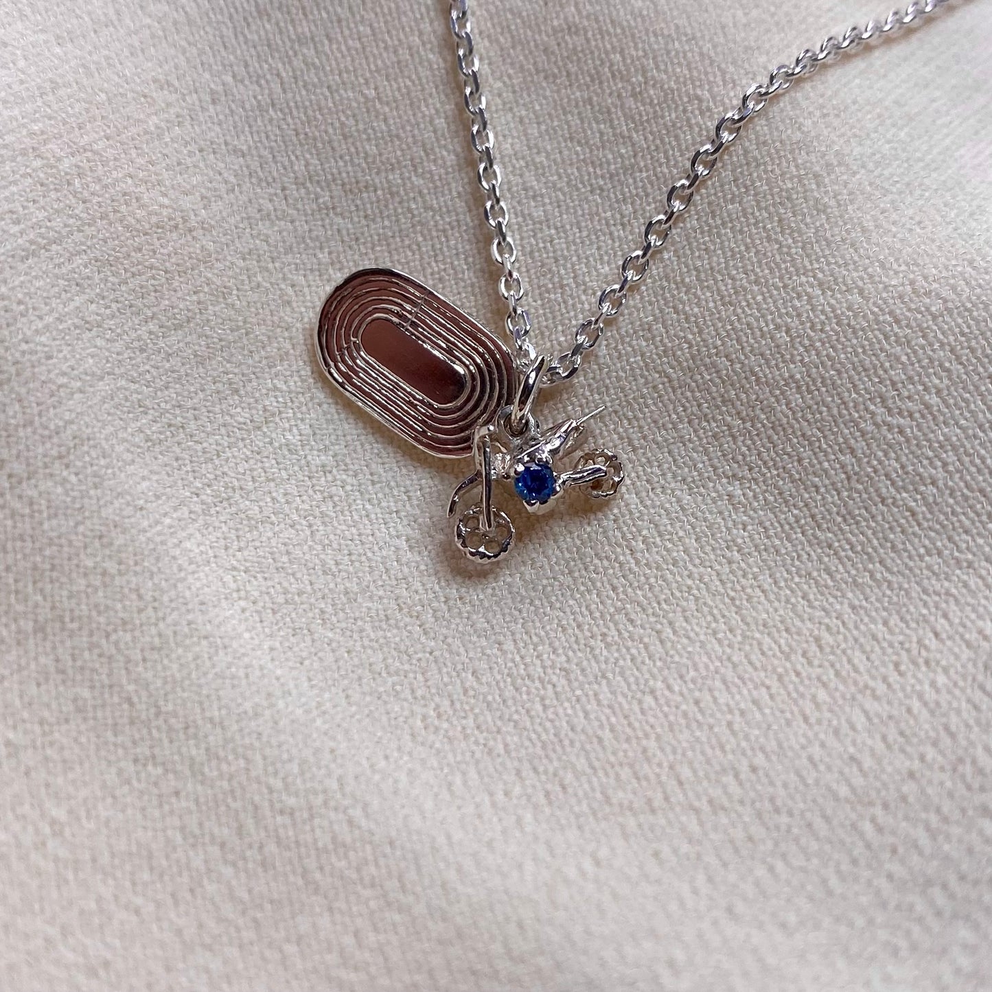 Ciondolo con moto da cross e pista di atletica